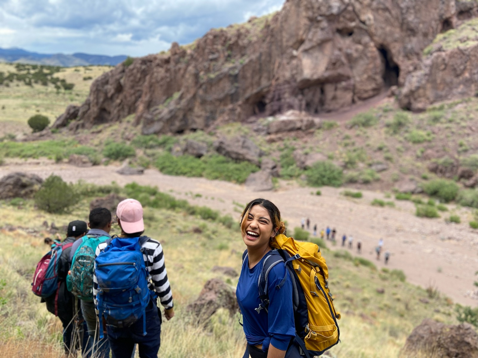 A young person wearing a backpack looks back at the camera and smiles